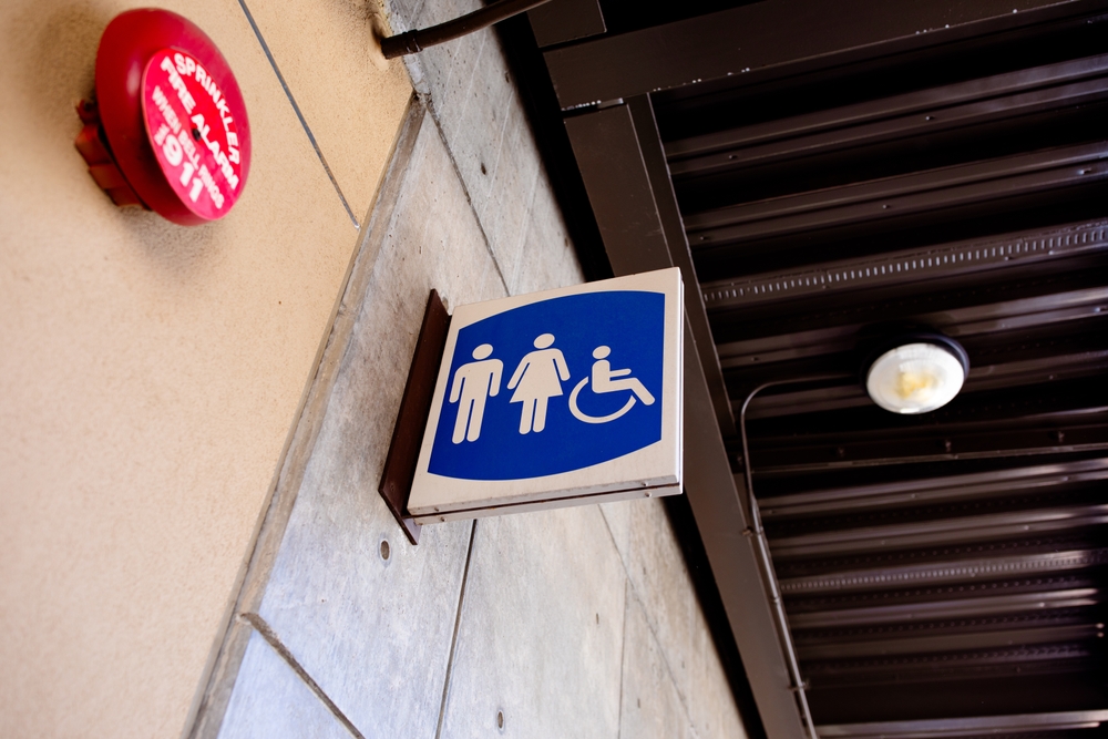 ADA unisex restroom layout is one of the most important considerations for a facilities manager and organization, as illustrated by this blue-and-white unisex bathroom sign on the wall of a public restroom.